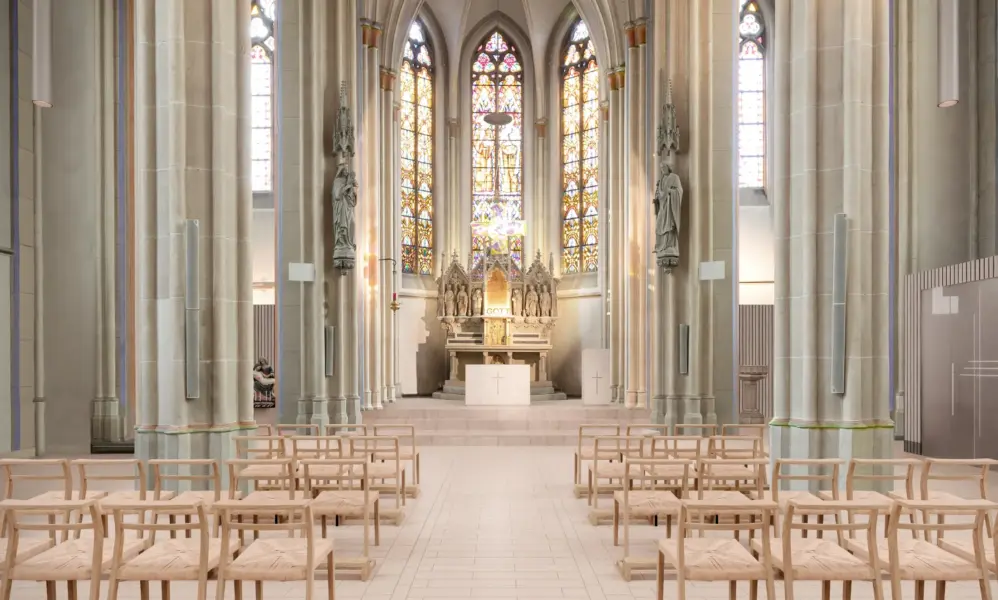 Innenansicht einer gotischen Kirche mit hohen Decken, bunten Glasfenstern und Holzbänken vor dem Altar